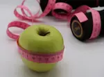 Close-up of green apple with pink measuring tape