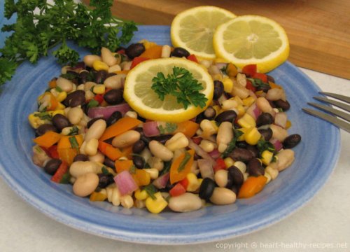 Bean salad with corn, red peppers, jalapeño, cilantro, along with red onion, scallion onions, and garnished with cilantro.