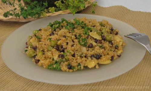 Almond orange quinoa on serving plate with herbs in background.