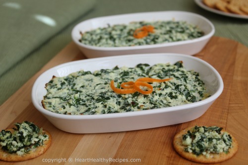 Spinach dip presented in two serving dishes garnished with carrot curls.