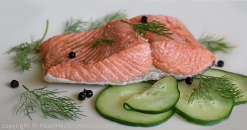 Salmon with cucumber slices, black peppers, and dill sprigs.