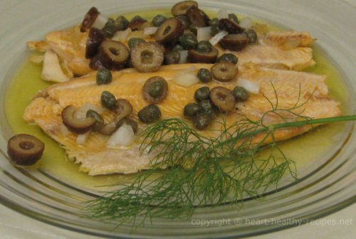 Trout fish topped with black olives and dill sprig.