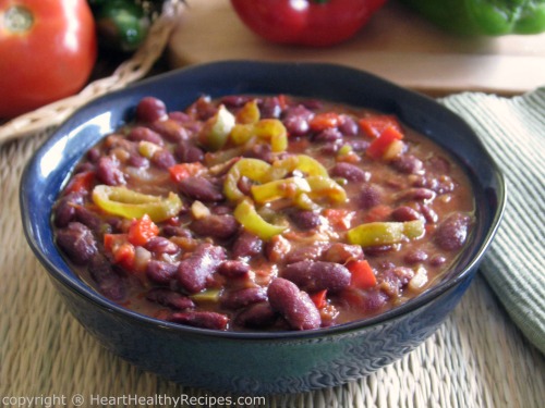 Bowl of vegetarian chili topped with sliced jalapeño peppers.