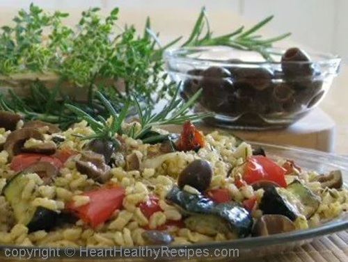 Mediterranean food highlighting black olives and fresh herbs.