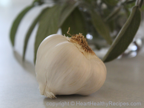 Whole garlic on counter with sage in the background.