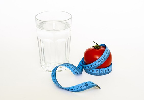 Glass of water with red tomato.