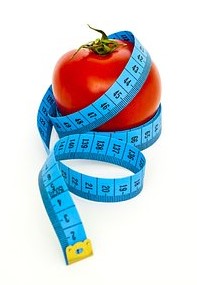 Red medium-sized tomato with blue measuring tape creatively wrapped around tomato.