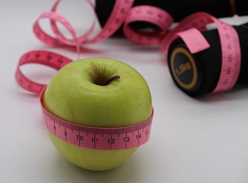 Close-up of green apple with pink measuring tape