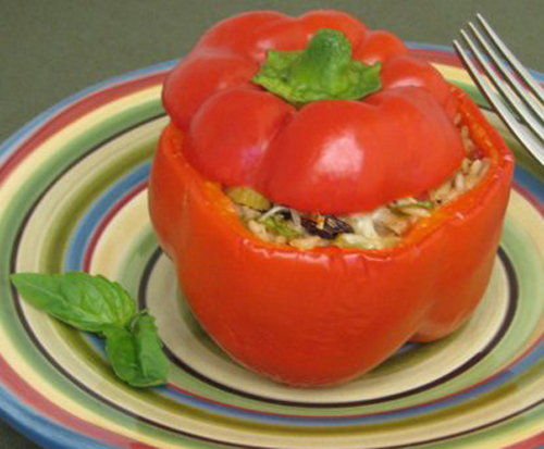 Close-up of stuffed Mediterranean bell pepper with basil garnish.