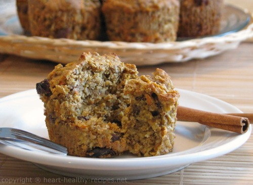 Close-up of sweet and spicy carrot muffins, along with two cinnamon sticks. Also, whole carrot muffins in the background.