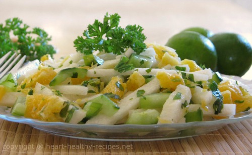 Jicama salad made of orange and lime slices along with chopped cucumber, cilantro and lemon juice. Topped with sprig of cilantro.