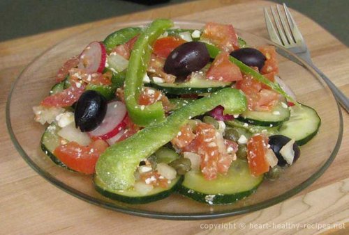 Greek salad consisting of sliced cucumbers, radishes, bell peppers, tomatoes, along with feta cheese and black olives.