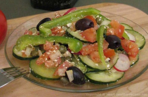 Greek salad consisting of sliced cucumbers, radishes, bell peppers, tomatoes, along with feta cheese and black olives.