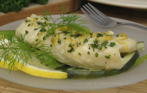 Cod fish topped with heart healthy seasonings and garnished with dill weed sprigs, along with lemon wedges to the side.