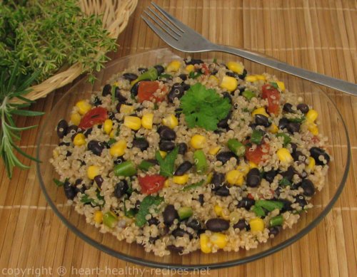 Black bean quinoa on serving plate topped with parsley garnish and herbs to the side.