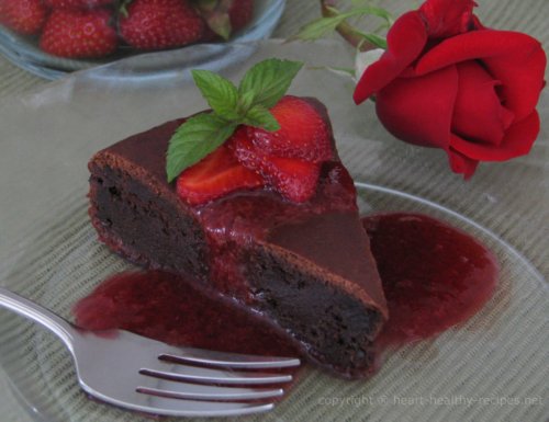 Chocolate cake topped with prune sauce, sliced strawberries and garnished with mint sprig.