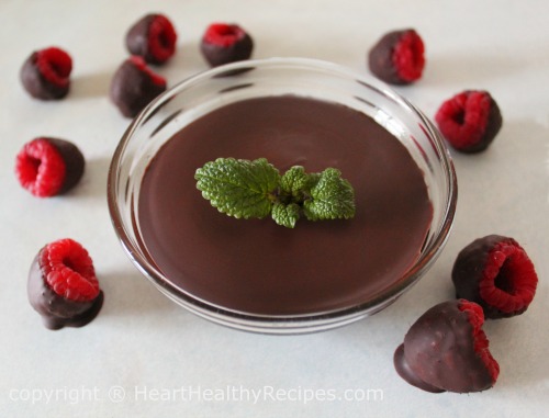 Chocolate covered raspberries surrounding chocolate topped with mint sprig.