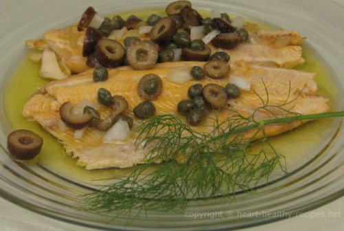 Trout fish topped with black olives and dill sprig.