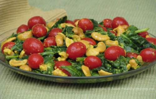 Salad made of fresh spinach, grape tomatoes, raw cashews, basil, ginger and drizzled with heart healthy olive oil.