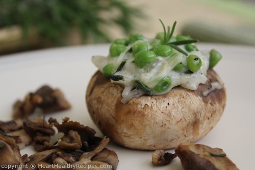 Close-up picture of stuffed mushroom with petite green peas and rosemary sprig.