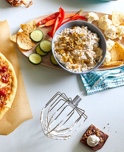Deluxe Electric Stand Mixer attachment on countertop with an assortment of snack foods.