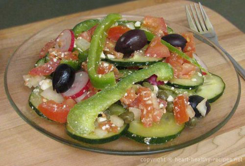 Greek salad of green peppers, black olives, red tomatoes, cucumbers, radishes, and more.