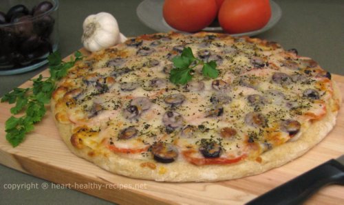 Homemade Mediterranean style pizza topped with olives and tomatoes, along with parsley for garnish.
