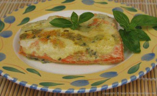 Salmon fillet on serving plate topped with sauce and basil garnish.