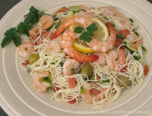 Shrimp pasta with green olives, tomatoes and garnished with lemon slice and parsley.