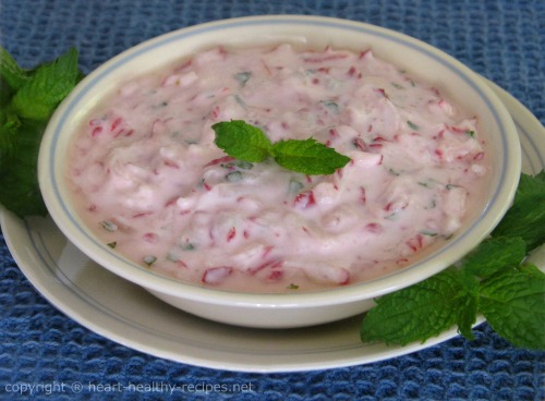 Mint radish sauce topped with mint sprig and surrounded by mint sprigs.