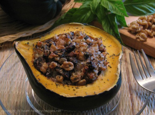 Stuffed acorn squash of raisins and walnuts with basil in background.