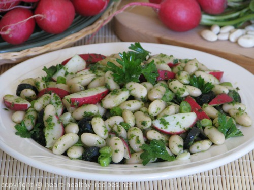 White bean salad with radishes, black olives, green onions, along with parsley-including parsley garnish on top.